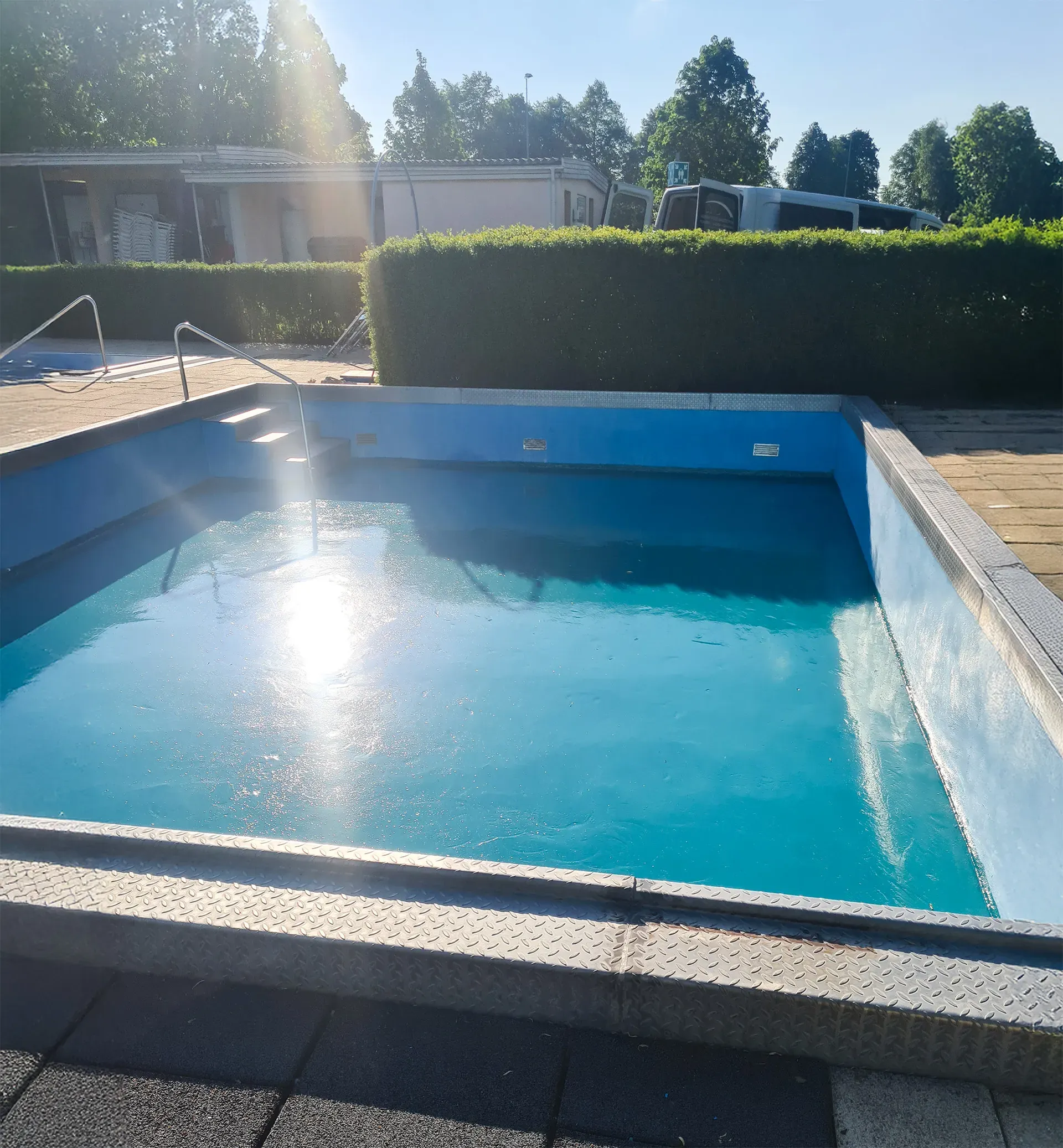 Schwimmbecken im Außenbereich frisch mit Wasser befüllt bei sonnigem Wetter