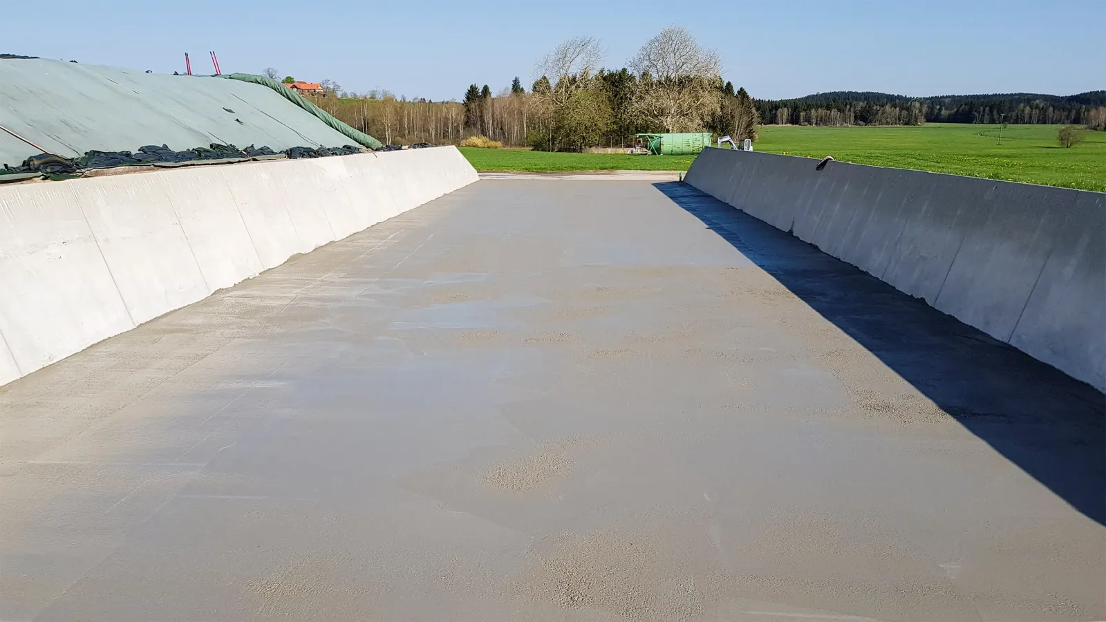frisch betonierte Fläche in einer landwirtschaftlichen Anlage umgeben von grüner Landschaft