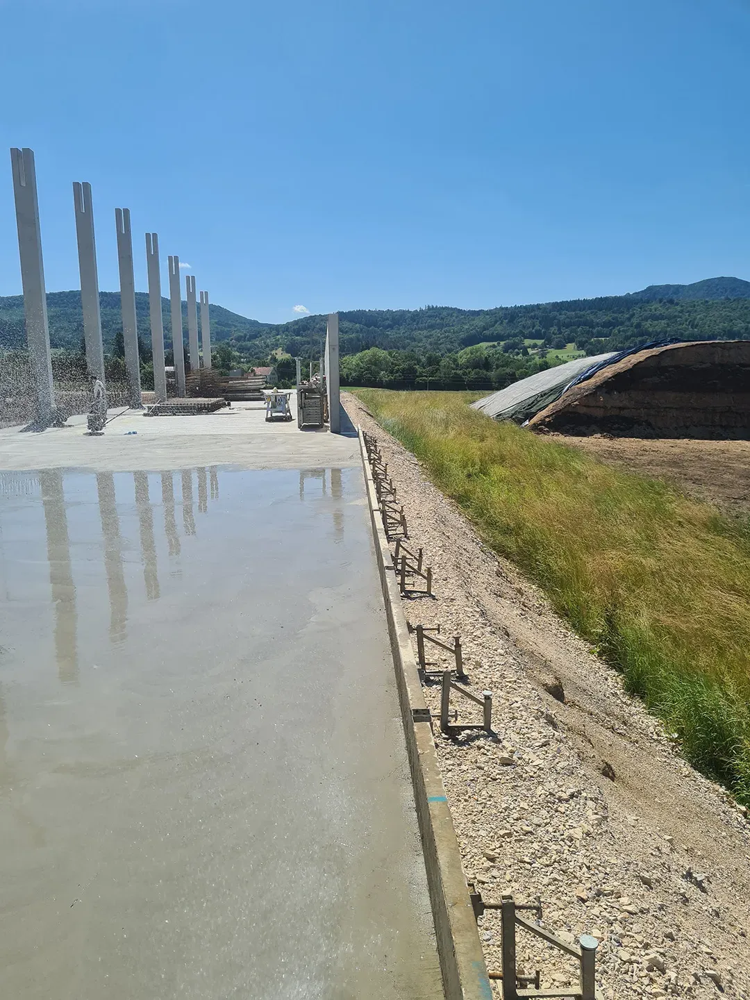 fertige Betonfläche neben einer Siloanlage und offenen Feldern mit Bergblick