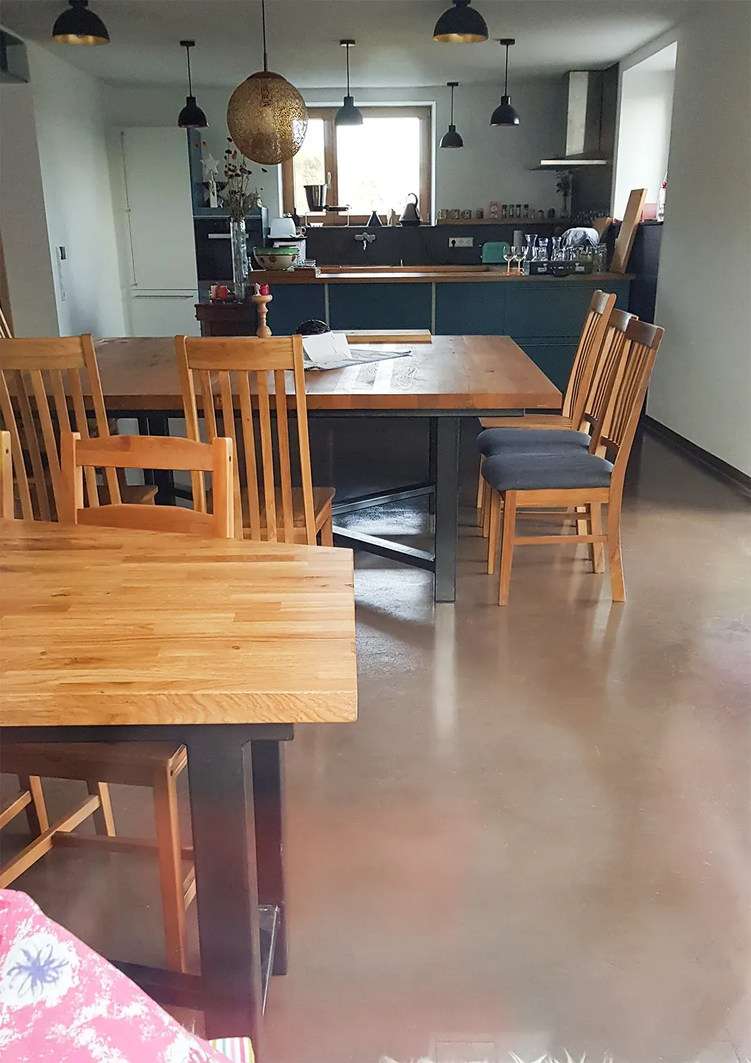 Ess- und Kochbereich mit Holzmöbeln, einer großen Arbeitsfläche und mehreren Hängeleuchten