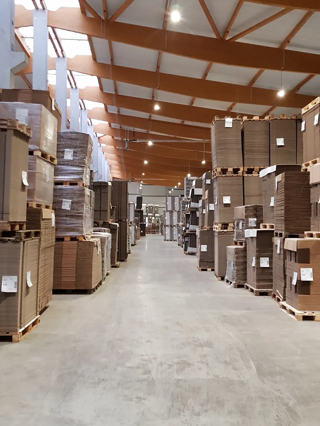 Industriehalle mit gestapelten Palettenmaterialien und hochwertiger Beleuchtung