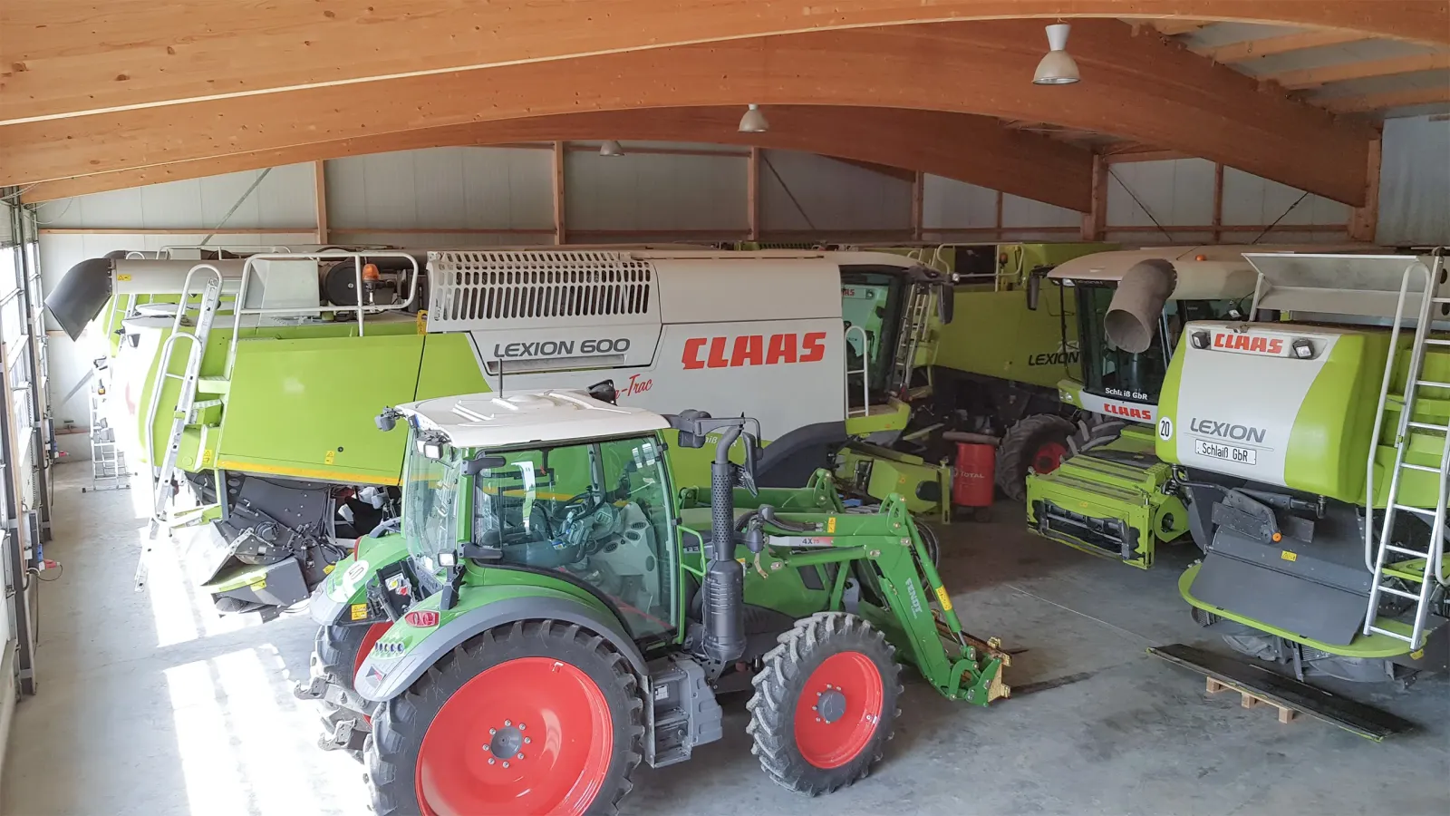 landwirtschaftliche Maschinen inklusive Traktor und Mähdreschern in großer Halle mit Holzdach