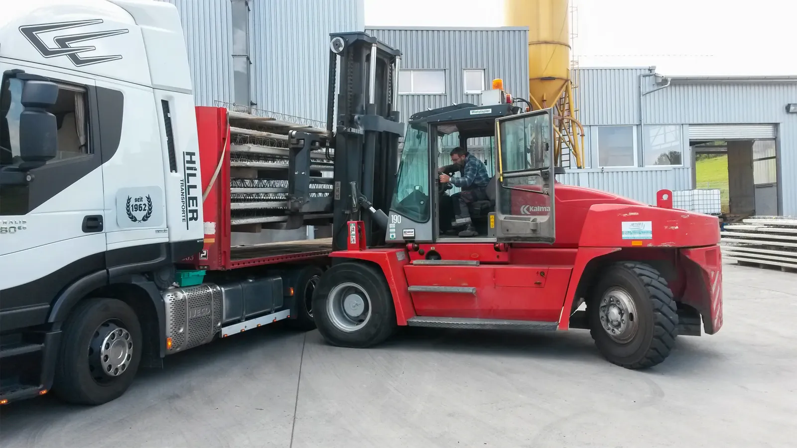 roter Gabelstapler beim Be- und Entladen eines LKW mit Baumaterialien